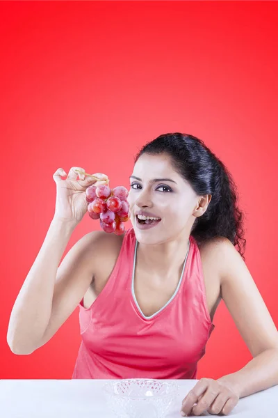 Mujer con uvas sobre fondo rojo — Foto de Stock