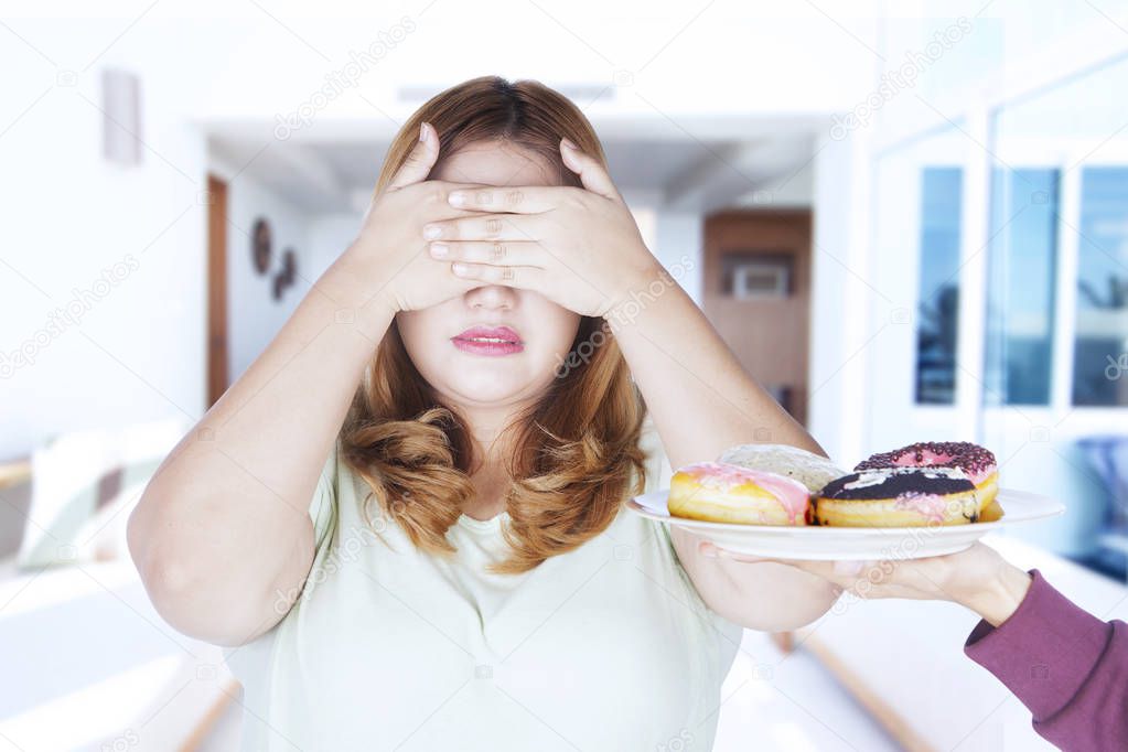 Fat woman reject donuts on plate 