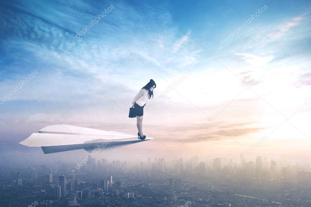 Female worker flying on paper aeroplane