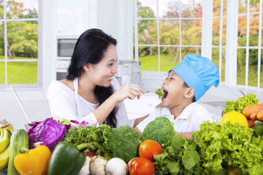 Happy mother gives her son fresh salad