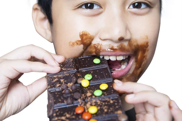 Чарівний хлопчик кусає шоколад на студії — стокове фото