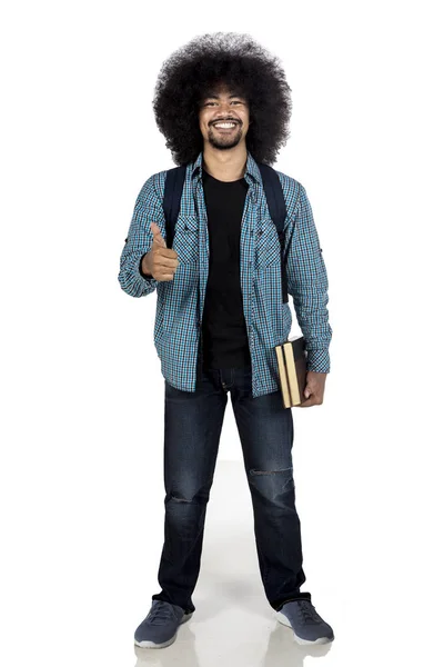 Estudante universitário mostrando polegar com livro — Fotografia de Stock