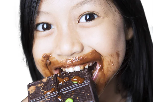 Menina bonito comer um chocolate no estúdio — Fotografia de Stock