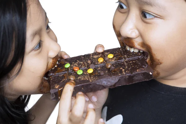 Two greedy sibling is eating a chocolate — Stock Photo, Image