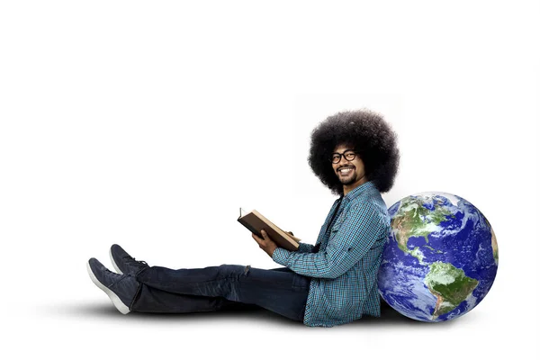 Young student sitting with globe and book — Stock Photo, Image