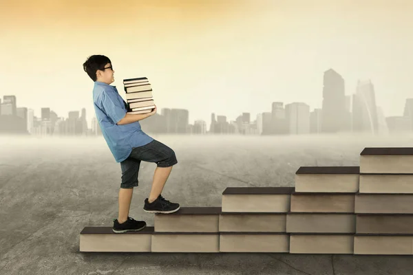 Хлопчик тримає в руках книг і ходити по книги сходові — стокове фото
