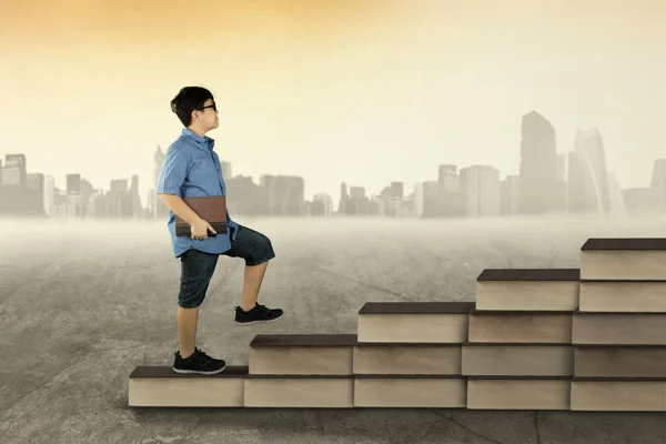Ragazzo con libro che cammina sulla scala dei libri — Foto Stock