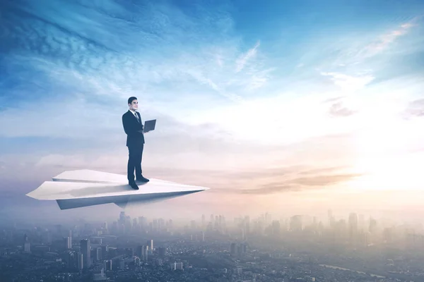 Бизнесмен на бумажном самолете с ноутбуком — стоковое фото
