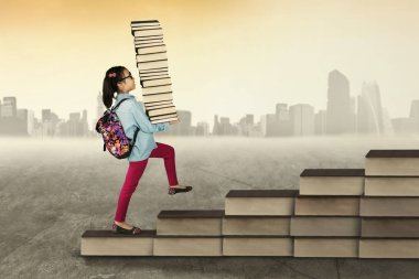 Kitap taşıyan ve yukarı doğru yürüyen kız