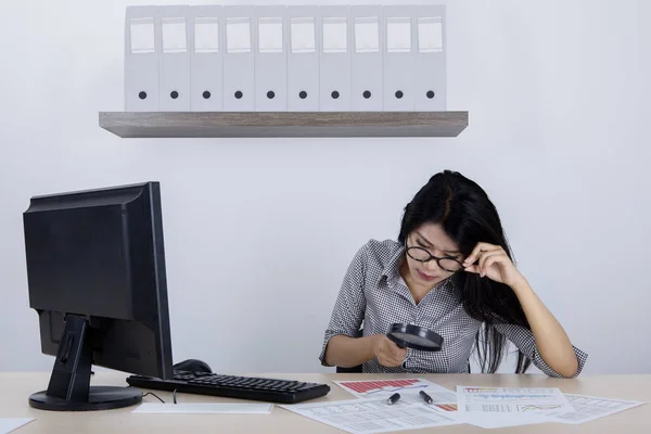 Unternehmerin mit Lupe im Büro — Stockfoto