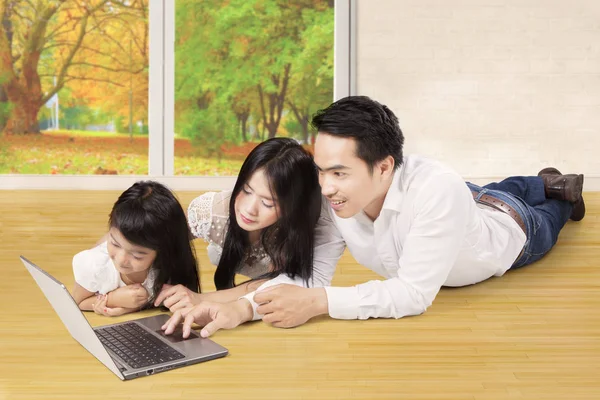 Menina e pais usam laptop no chão — Fotografia de Stock