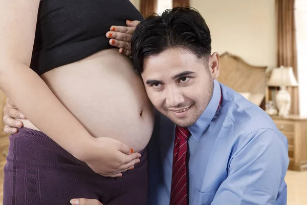 Marido ouve barriga grávida — Fotografia de Stock