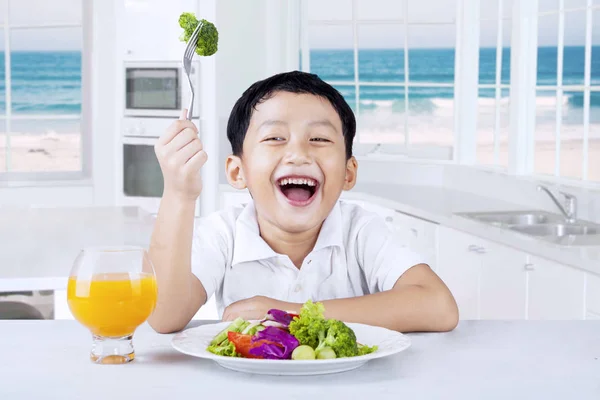 Bambino che mangia insalata di verdure in cucina — Foto Stock