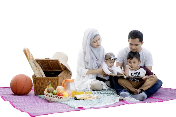 Muslimsk familj läser en bok i picknick — Stockfoto