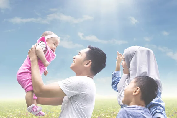 Família muçulmana brincando com bebê no prado — Fotografia de Stock