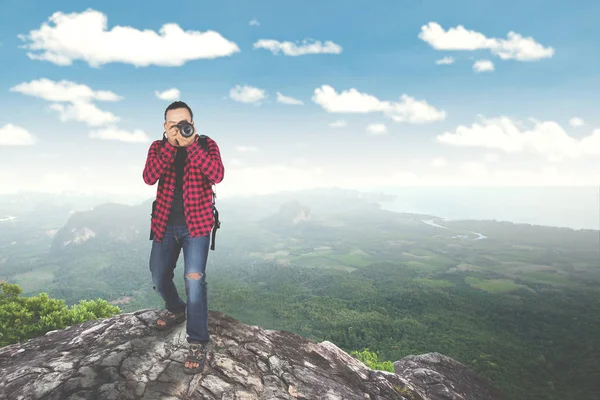 Молодой человек фотографирует на горе — стоковое фото