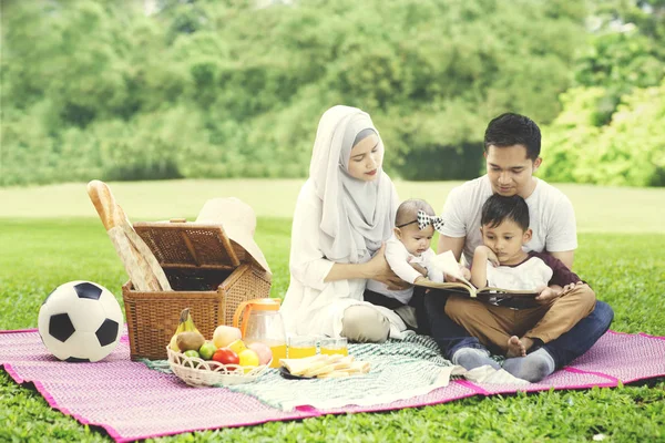 Asiático família piquenique com um livro — Fotografia de Stock