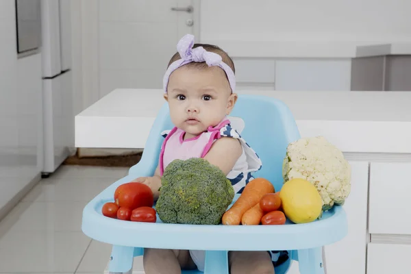 Μωρό κορίτσι που κάθεται σε καρέκλα με λαχανικά — Φωτογραφία Αρχείου