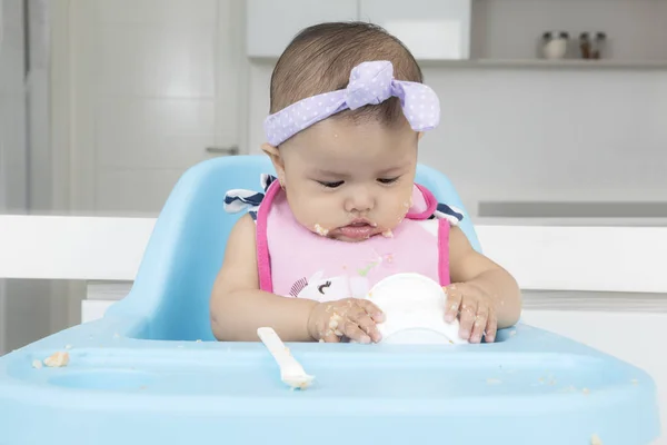 Bebé divertido comiendo comida en la cocina —  Fotos de Stock