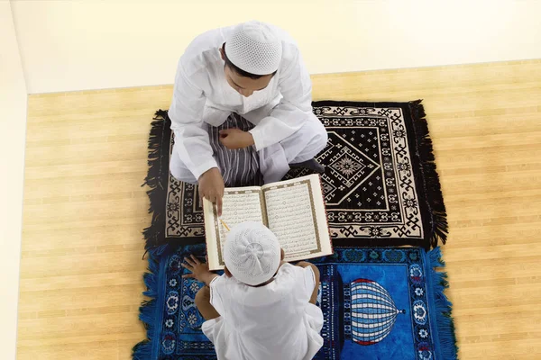 Pequeno filho e pai lendo o Alcorão juntos — Fotografia de Stock
