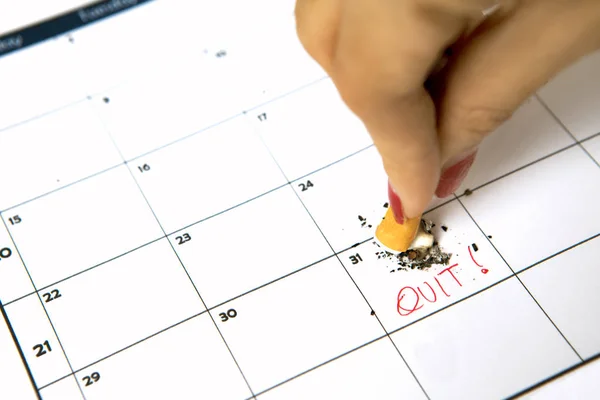 Vrouw hand vernietigen sigaret op kalender — Stockfoto