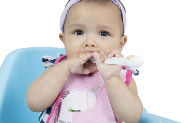 Cute baby holding spoon on chair — Stock Photo, Image