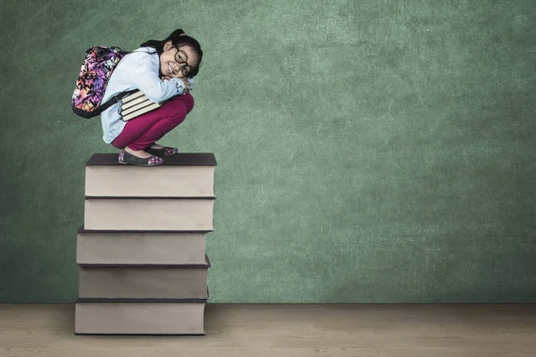 Petite fille squat sur pile de livres — Photo