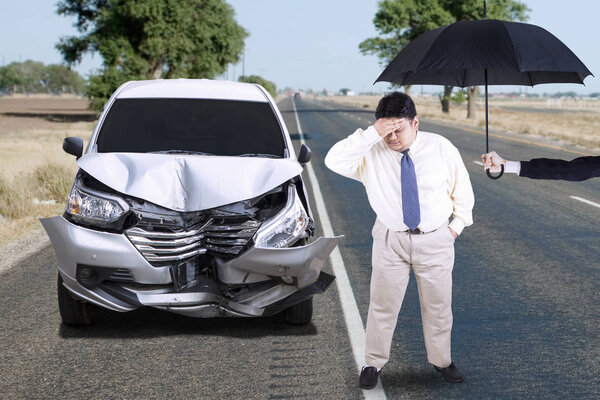 Человек с помятой машиной и зонтиком
