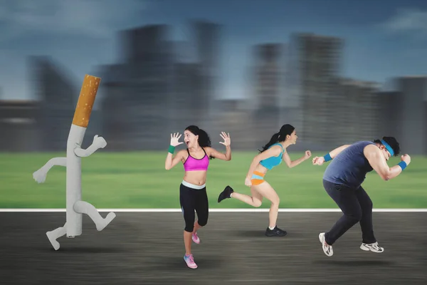 Runners chased by a cigarette — Stock Photo, Image