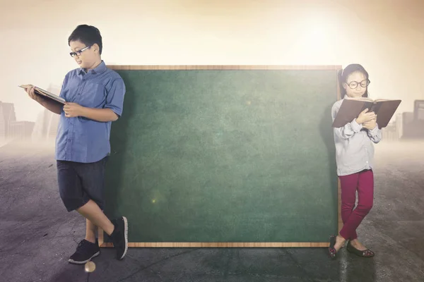 Two students lean with blank chalkboard — Stock Photo, Image