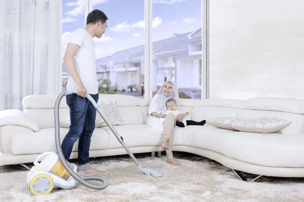 Jovem homem limpeza tapete em casa — Fotografia de Stock