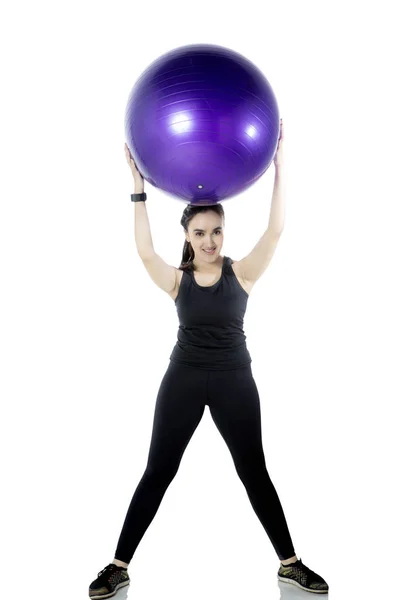 Mujer joven levantando pelota de fitness —  Fotos de Stock