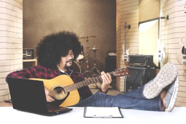 Afro adam masada dizüstü bilgisayar ile gitar çalmak 