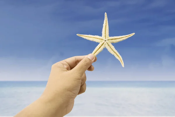 Hand holding zeester op strand — Stockfoto