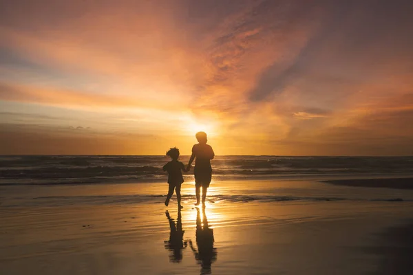 Gelukkige kinderen lopen op strand bij zonsondergang — Stockfoto
