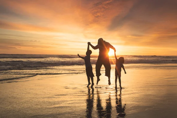 Feliz família pulando na praia — Fotografia de Stock