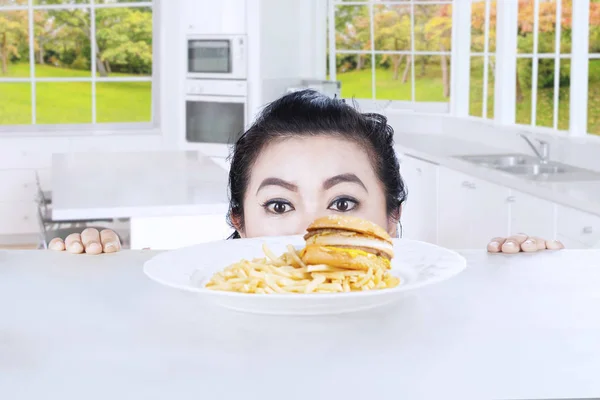 Cabeza de mujer con hamburguesa en la cocina — Foto de Stock