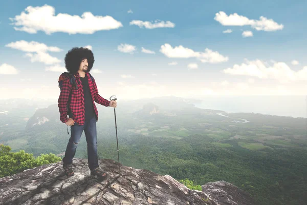 Hombre Afro excursionista escalada roca en colina — Foto de Stock