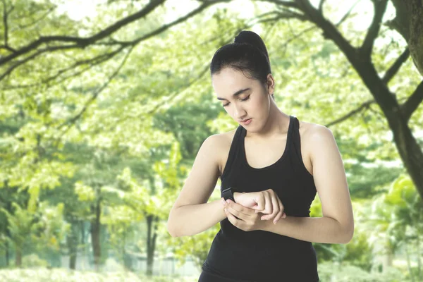 Hezká dívka používá smartwatch v parku — Stock fotografie