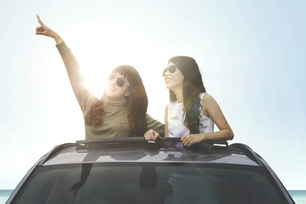 Dos hembras mirando algo en el techo solar del coche — Foto de Stock