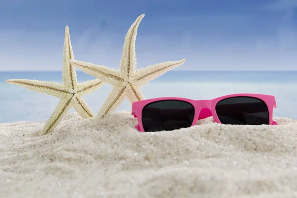 Sunglasses and sea stars at beach — Stock Photo, Image