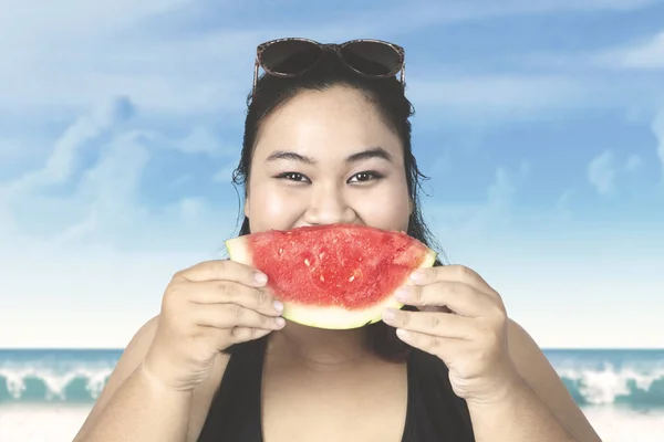 Gruba kobieta jedzenie świeżego arbuza na plaży — Zdjęcie stockowe