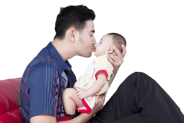 Отец целует своего ребенка на диване — стоковое фото