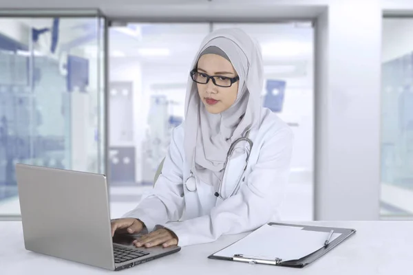 Muslimischer Allgemeinarzt arbeitet mit Laptop — Stockfoto