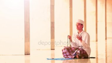 Müslüman adam dua eden boncuk camide tutar.
