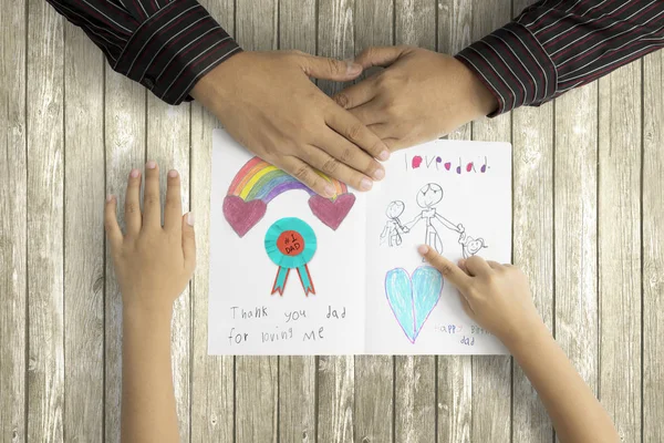 Niño mostrando imagen a padre en la tarjeta de felicitación — Foto de Stock