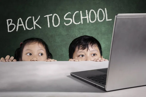 Barn gömmer sig med tillbaka till skolan text ombord — Stockfoto