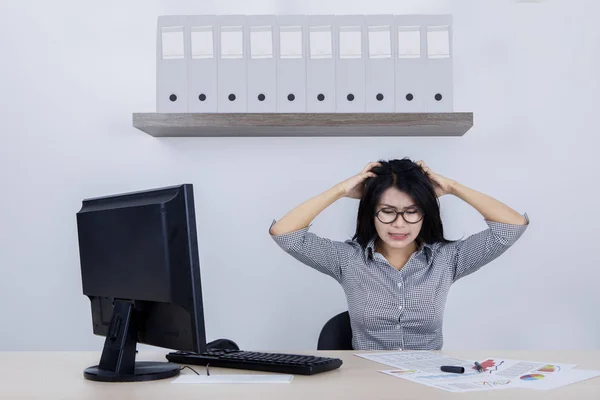 Empresária deprimida com um computador e papelada — Fotografia de Stock