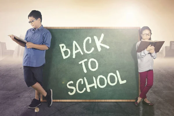 Elementary students lean with a chalkboard — Stock Photo, Image