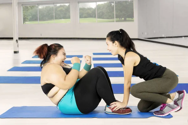 Dikke vrouw doen van sit up met een trainer — Stockfoto